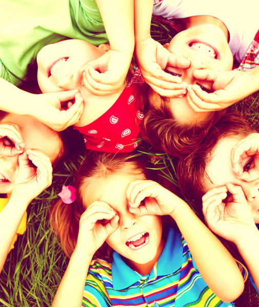 children looking up at the sky, laying in the grass